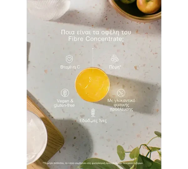 Center orange cup sits on a speckled countertop with Greek text about Fibre Concentrate benefits and small icons around it (Vitamin C, Fibre, vegan & gluten-free, natural sweetener).